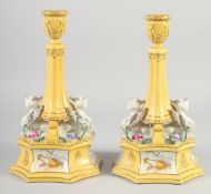 A PAIR OF CONTINENTAL YELLOW GROUND SPHINX CANDLE STICKS. 12ins high.