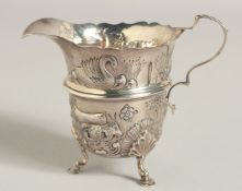 AN IRISH STYLE SILVER CREAM JUG repousse decoration on three claw feet. Birmingham 1912.