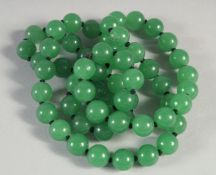 A STRING OF SIXTY GREEN JADE BEADS. 25ins long.