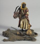 A COLD PAINTED BRONZE GROUP, an Arab man holding a deer's head and standing on a lion skin rug. 5.