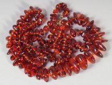 A GOOD AMBER GRADUATED NECKLACE, 108 beads, 29ins long, 44gms, with gold ring,