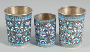 A PAIR OF RUSSIAN SILVER AND ENAMEL BEAKERS, 2.25ins and a smaller beaker, 1.75ins high. (3).