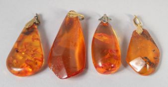 FOUR VARIOUS AMBER PENDANTS, 20gms.