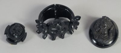 A WHITBY JET BRACELET AND TWO CARVED BROOCHES (3). 79gms.