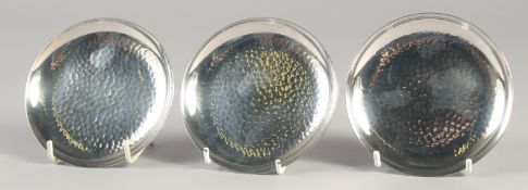 MITUKOSHI. A SET OF THREE HAMMERED SILVER CIRCULAR DISHES. 4.5ins diameter.