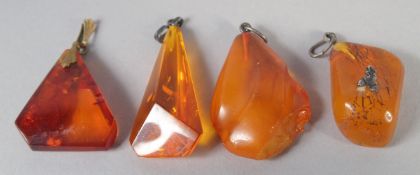FOUR VARIOUS AMBER PENDANTS, 21gms.