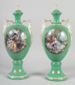 A PAIR OF CONTINENTAL GREEN GROUND TWO HANDLED URN SHAPED VASES AND COVERS. 14ins high.