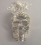 A SILVER FILIGREE SKULL PENDANT AND CHAIN.