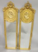 A PAIR OF GILTWOOD NARROW MIRRORS the upper panel with the bust of a lady. 5ft 10ins x 1ft 9ins.