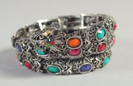 A SILVER SNAKE BRACELET set with various coloured stones.