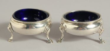 A SMALL PAIR OF GEORGE III SILVER CIRCULAR SALTS with bead edge, sapphire blue liner on three pad