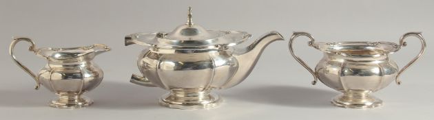 A GEORGE II SILVER THREE PIECE TEA SET, with shell mounts, comprising: tea pot, sugar basin, milk
