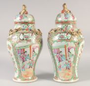 A PAIR CHINESE CANTON FAMILLE ROSE VASES AND COVERS, painted with panels of figures, the covers with