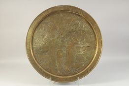 A LARGE EMBOSSED AND CHASED BRASS TRAY, depicting a mythological scene with animals, 59cm diameter.