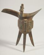 AN EARLY CHINESE BRONZE RITUAL JUE CUP, with spout and raised on three legs, 20cm high.