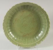 A LARGE CHINESE CELADON GLAZE CHARGER, with central carved dragon and foliate rim, 50.5cm diameter.