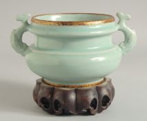 A CHINESE CELADON TWIN HANDLED CENSER AND STAND, the handles moulded as fish, characters to the