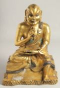 A LARGE GILDED BRONZE FIGURE OF A SEATED DEITY holding a vajra and book, the figure with silver
