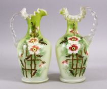 A 19TH CENTURY PAIR OF OPALINE GLASS MOULDED JUGS, with a moulded rim and floral painted decor, 25cm