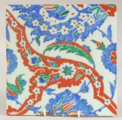 AN IZNIK GLAZED POTTERY TILE, with decorative floral sprays, 25cm square.