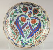 A TURKISH OTTOMAN GLAZED POTTERY PLATE, painted with sprays of flora, 31.5cm diameter.