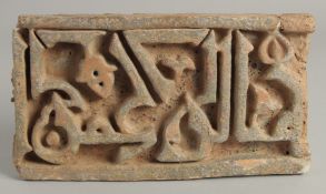 AN ISLAMIC STONE TILE WITH KUFIC SCRIPT, 26cm x 14.5cm.