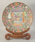 A LARGE CHINESE PORCELAIN PLATE AND WOODEN STAND, the plate painted with a scene of figures and