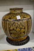 A large Chinese earthenware jar and cover on a hardwood stand.