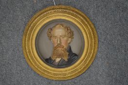 A painted circular cast iron plaque commemorating Charles Dickens.