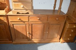 A pine sideboard with three drawers and three cupboard doors.