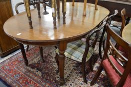 A mahogany extending dining table with a central leaf on reeded turned legs.