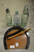 A horseshoe shaped crumb tray and brush and three old bottles.