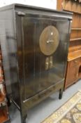 A Chinese black lacquer two door wardrobe with fitted interior.