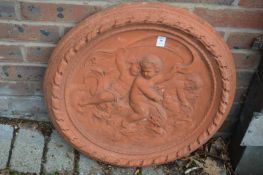 A circular terracotta plaque decorated with cherubs.