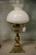 An ornate brass and glass oil lamp with opaque glass shade.