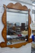 A marquetry inlaid mahogany mirror with shaped frame.
