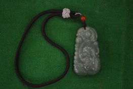 A Chinese carved jade pendant suspended from a cord.