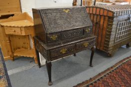 An 18th century carved oak bureau on stand.