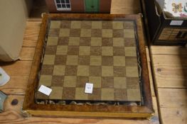 Decorative chess set with cast metal pieces and smoked glass playing surface.