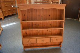 A pine shelving unit with three small drawers.
