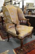 An 18th/19th century French carved walnut open wing armchair with classical style upholstery on