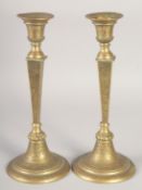 A PAIR OF ISLAMIC BRASS CANDLESTICKS, the bases with calligraphy, 31cm high.