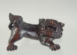 A CARVED WOODEN NETSUKE of a lion dog, 6cm widest point.