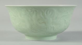 A CHINESE CELADON CARVED DRAGON RESTAURANT BOWL, with characters to the base, 15cm diameter.