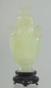 A CHINESE CARVED JADE LIDDED VASE AND WOODEN STAND, the vase with foo dog finial and drop ring