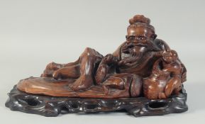 A CHINESE CARVED HARDWOOD FIGURE OF AN IMMORTAL, on a fitted hardwood stand, 40cm long overall.