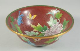 A LARGE CHINESE RED GROUND CLOISONNE BOWL, decorated with native flora, 25.5cm diameter.