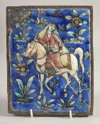 A PERSIAN QAJAR GLAZED POTTERY TILE, depicting a figure on horseback and flora, inset within an