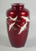 A JAPANESE ANDO RED GROUND CLOISONNE VASE, decorated with enamelled cranes, the rims with white