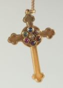 A 9CT GOLD CROSS on a chain, the cross inset with gemstones.